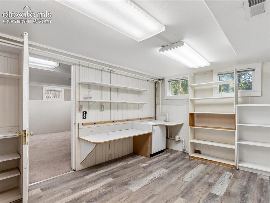 Image 20 of 35: Versatile room featuring wood-finish flooring, built-in shelving, a built-i