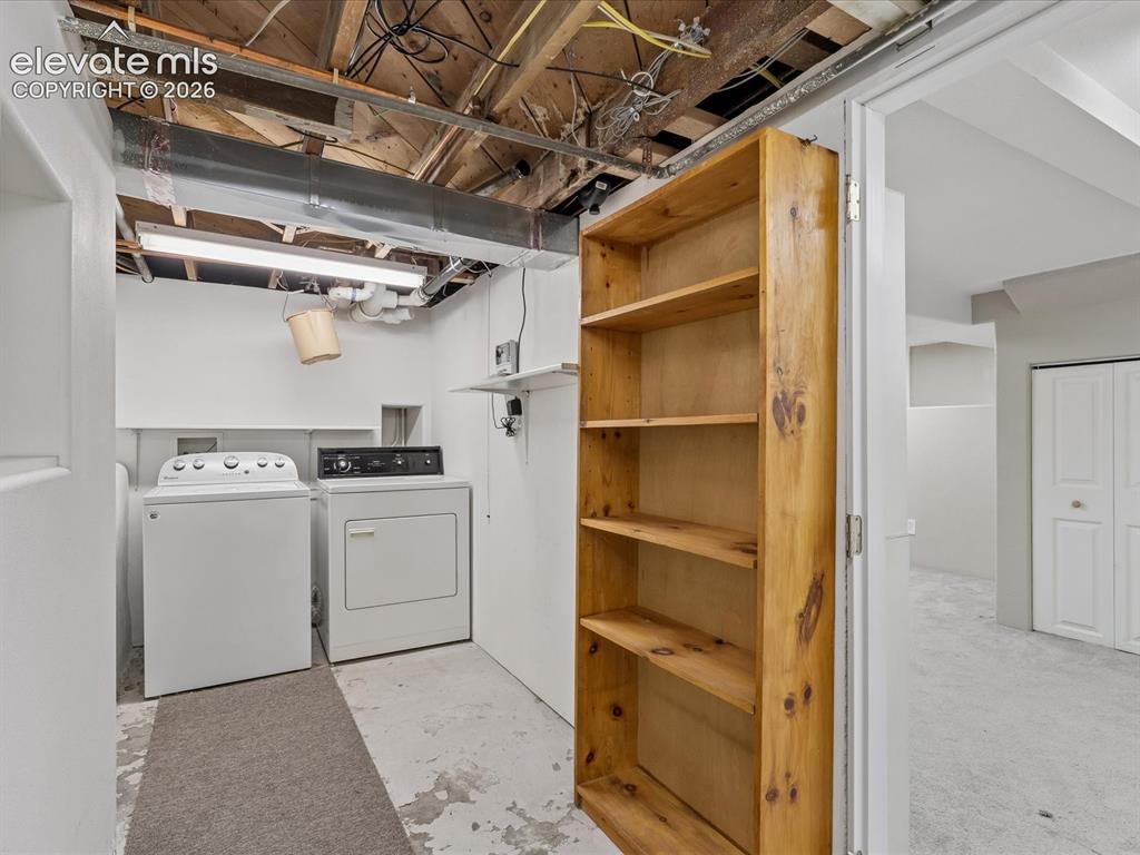 Image 21 of 35: Dedicated laundry area with a washer and dryer, accompanied by a multi-shel
