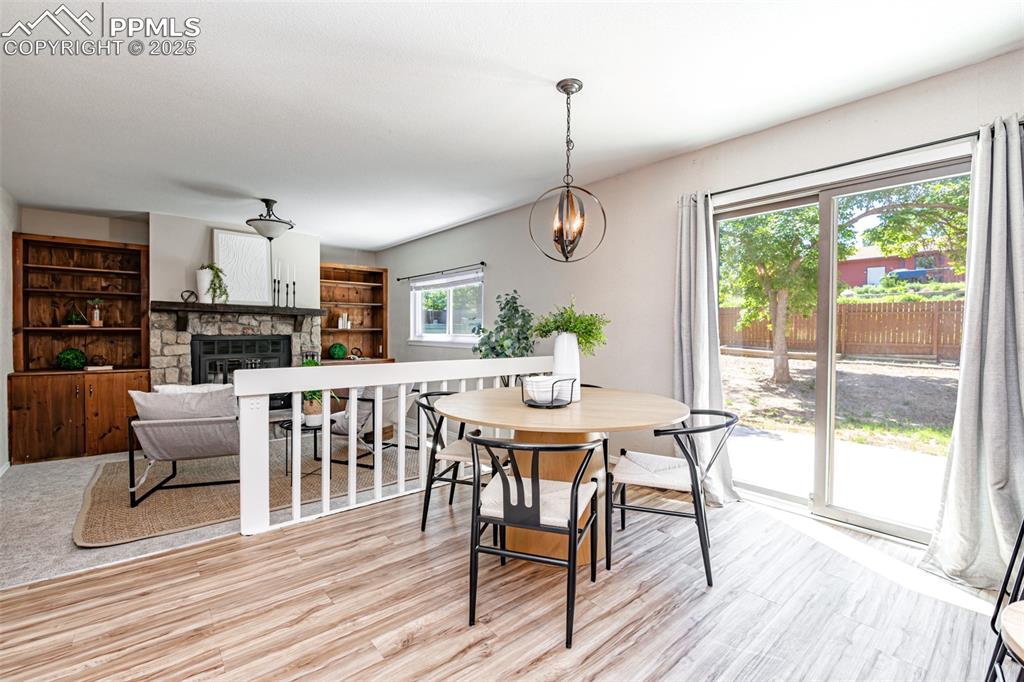 Image 13 of 38: Dining room featuring light wood finished floors, a fireplace, and a chande