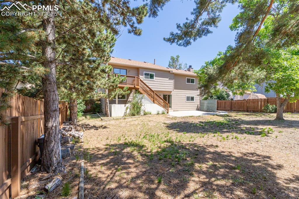 Image 18 of 38: Rear view of house featuring stairs, a fenced backyard, a patio, a chimney,