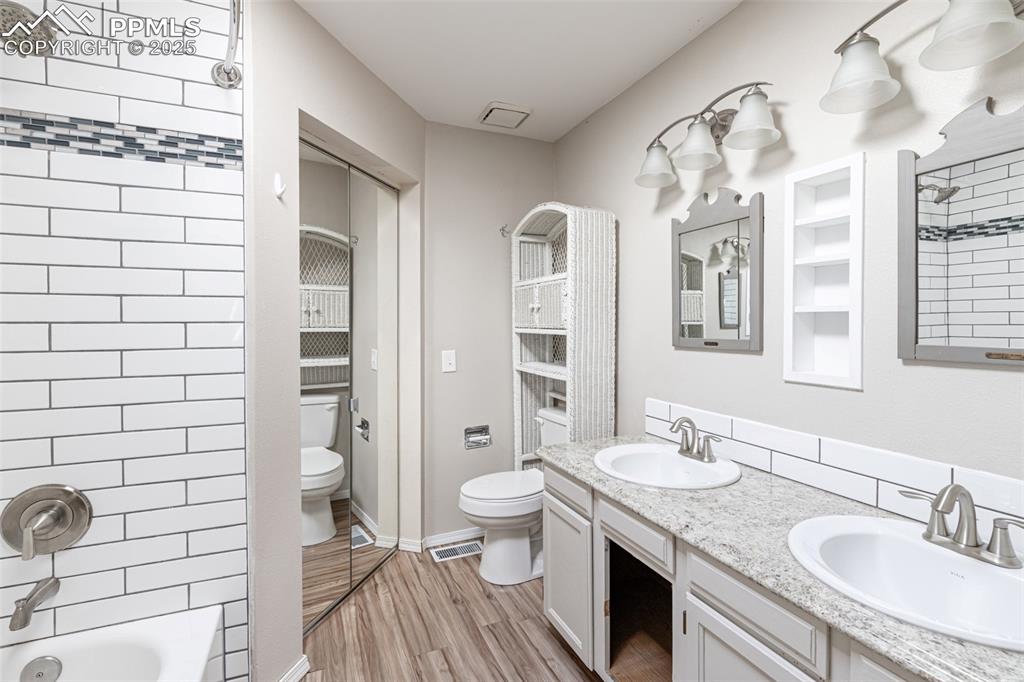 Image 25 of 38: Bathroom with double vanity, wood finished floors, and shower / washtub com