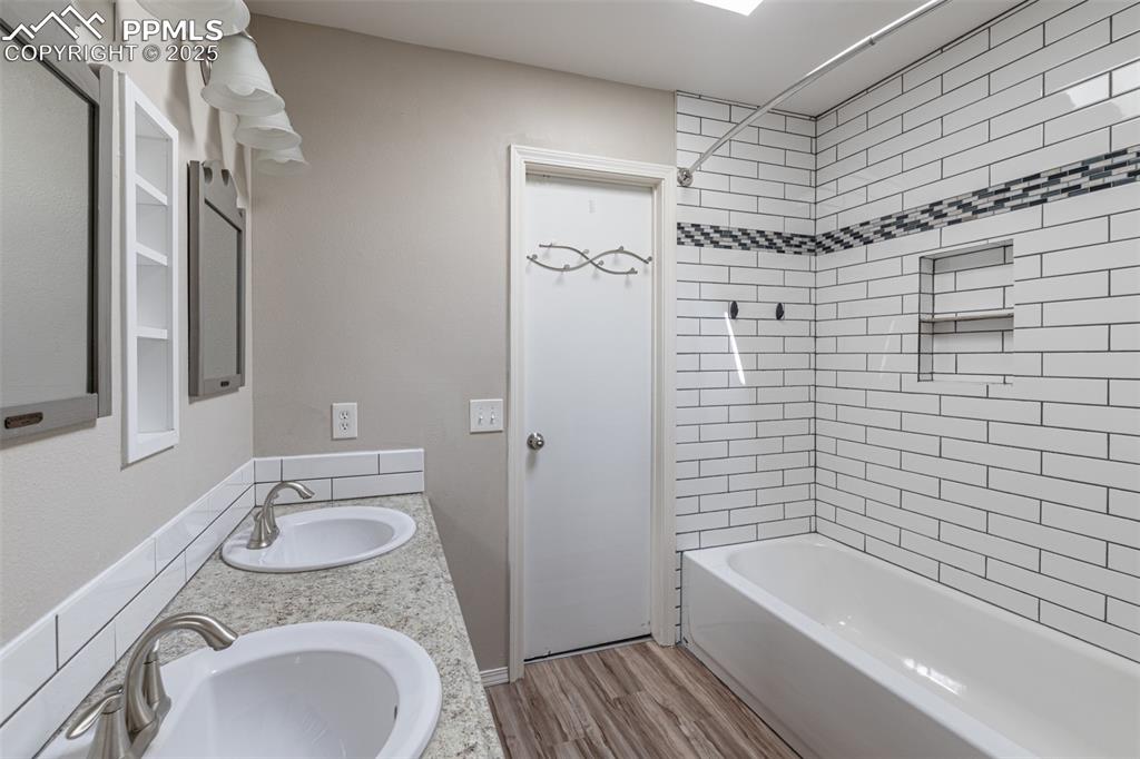 Image 26 of 38: Full bath featuring double vanity, wood finished floors, and washtub / show