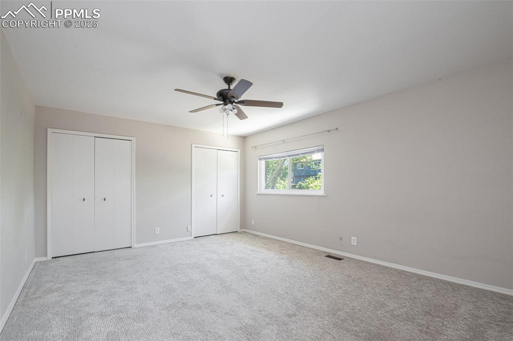 Image 30 of 38: Unfurnished bedroom featuring two closets, carpet flooring, and ceiling fan