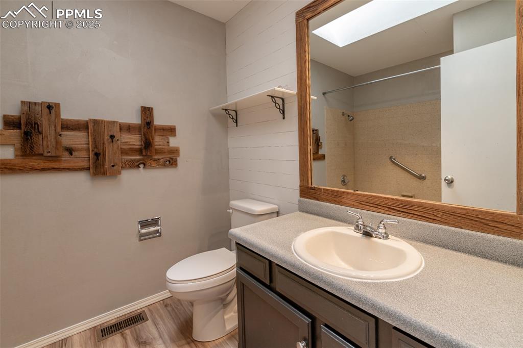 Image 32 of 38: Bathroom with a skylight, wood finished floors, and vanity