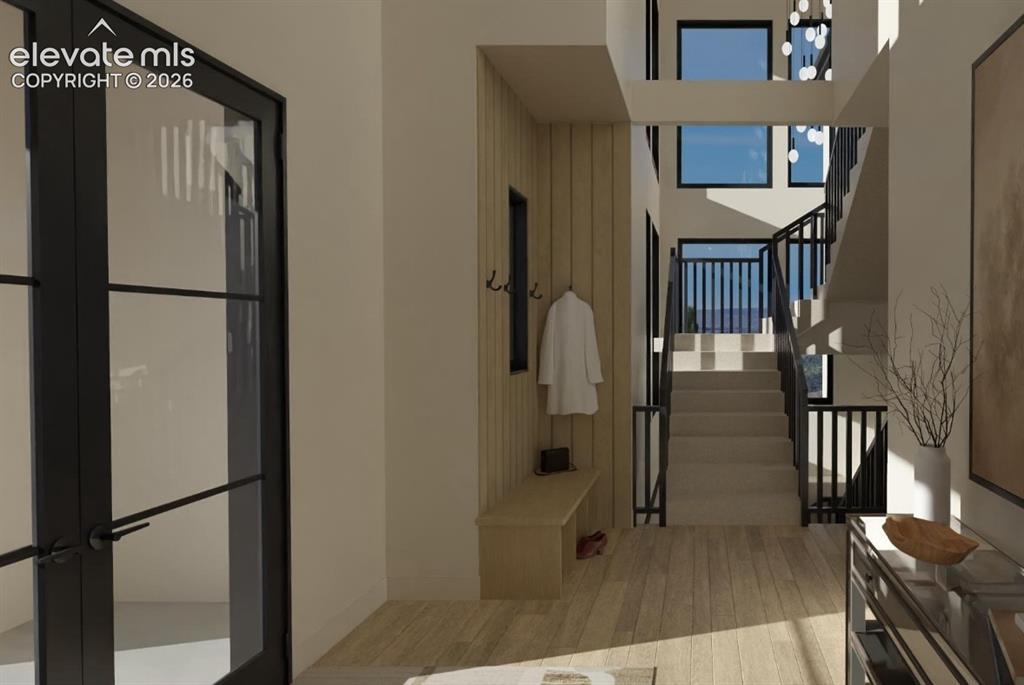 Image 17 of 32: Two story entry with custom iron double doors, iron railings, and white oak