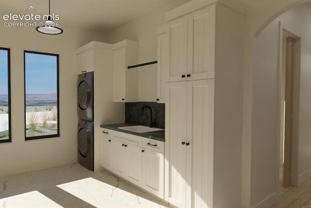 Image 21 of 32: Laundry area featuring white cabinetry, integrated sink with matte black fa