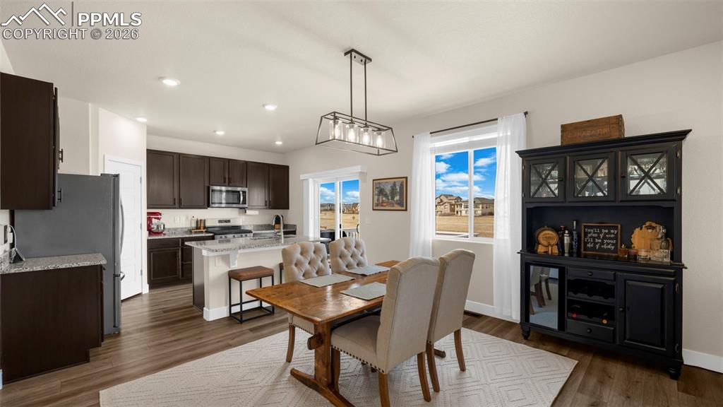 Image 30 of 43: Dining room with dark wood-style flooring and recessed lighting