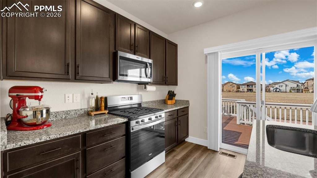 Image 32 of 43: Kitchen with dark wood finish cabinets, stainless steel appliances, light s