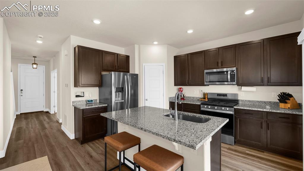Image 34 of 43: Kitchen with light stone countertops, a breakfast bar, stainless steel appl