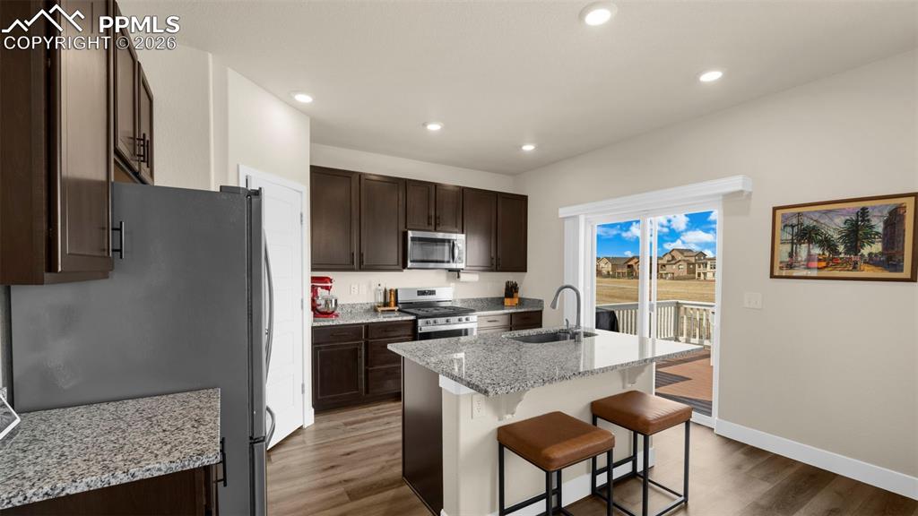 Image 35 of 43: Kitchen with dark wood finish cabinets, light stone countertops, light wood