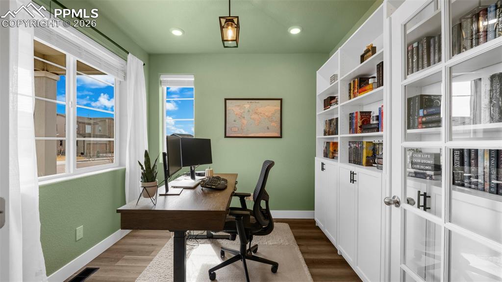 Image 36 of 43: Home office with dark wood-style flooring and recessed lighting