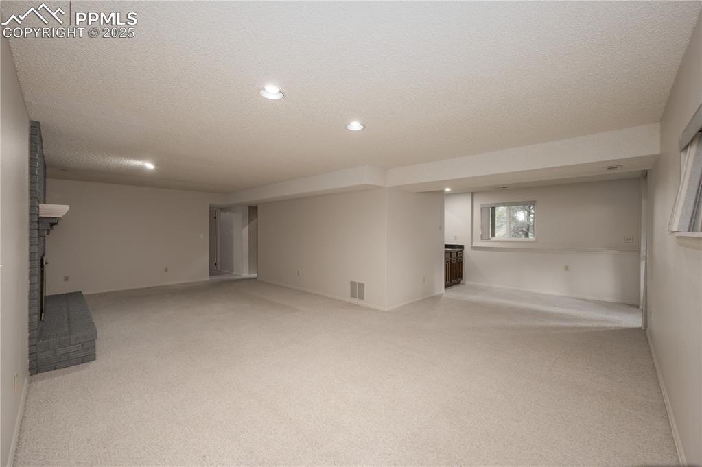 Image 19 of 34: Lower level rec room with fireplace