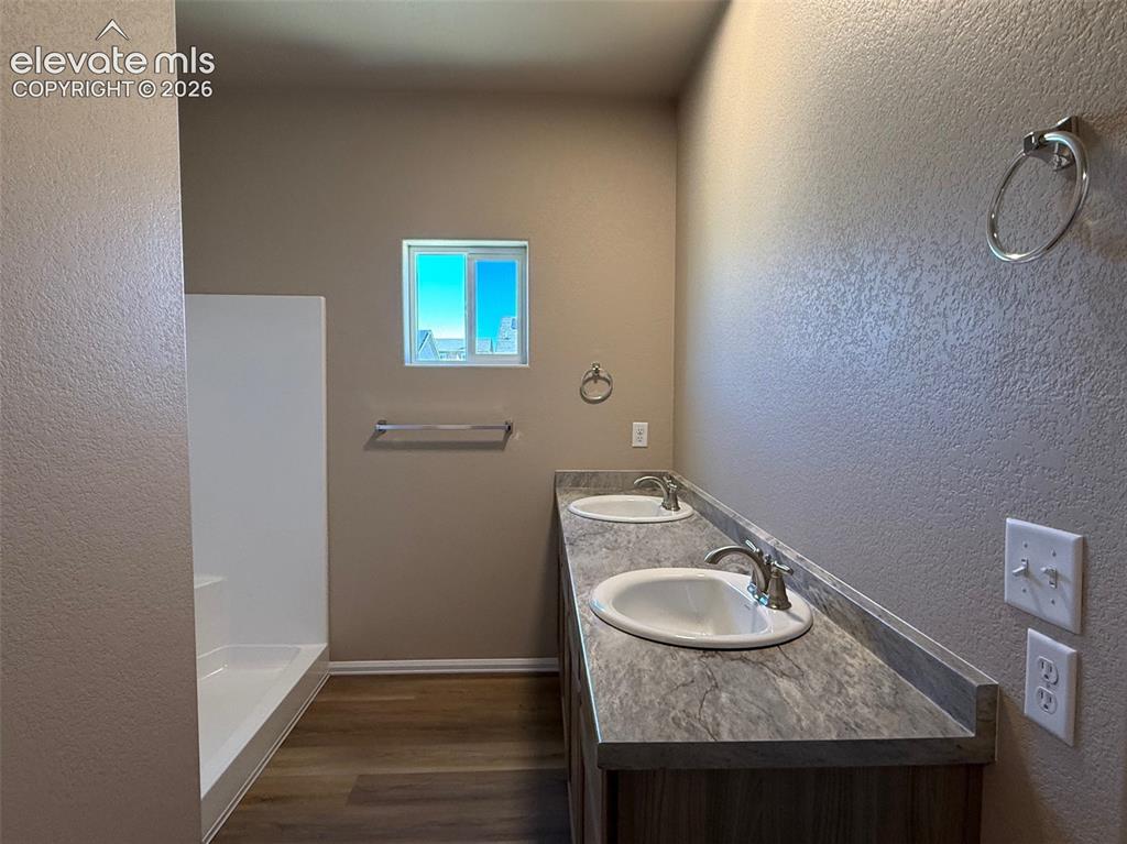 Image 15 of 34: Dual undermount sinks, stone-look countertop, wood-finish vanity, and a win