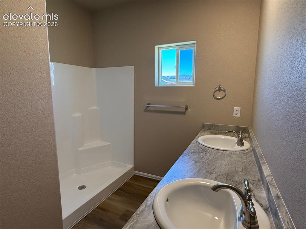 Image 16 of 34: Dual vanity with integrated sinks, brushed nickel fixtures, wood-finish flo