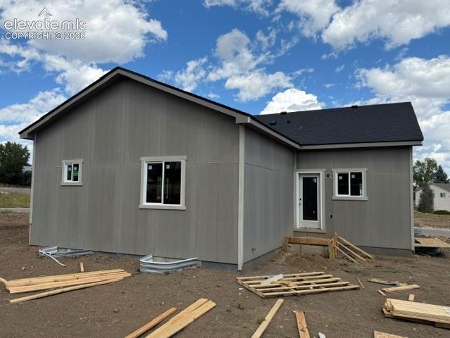 Image 2 of 34: Grey siding exterior with a black shingle roof, white trim windows, and a w