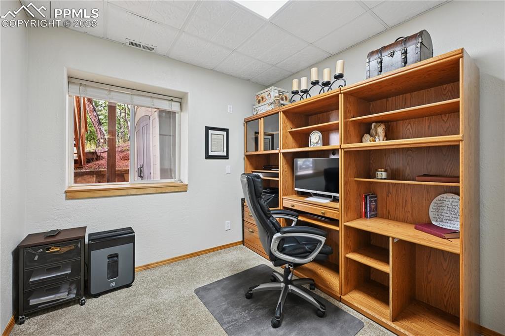 Image 14 of 34: Office area with light colored carpet and a paneled ceiling