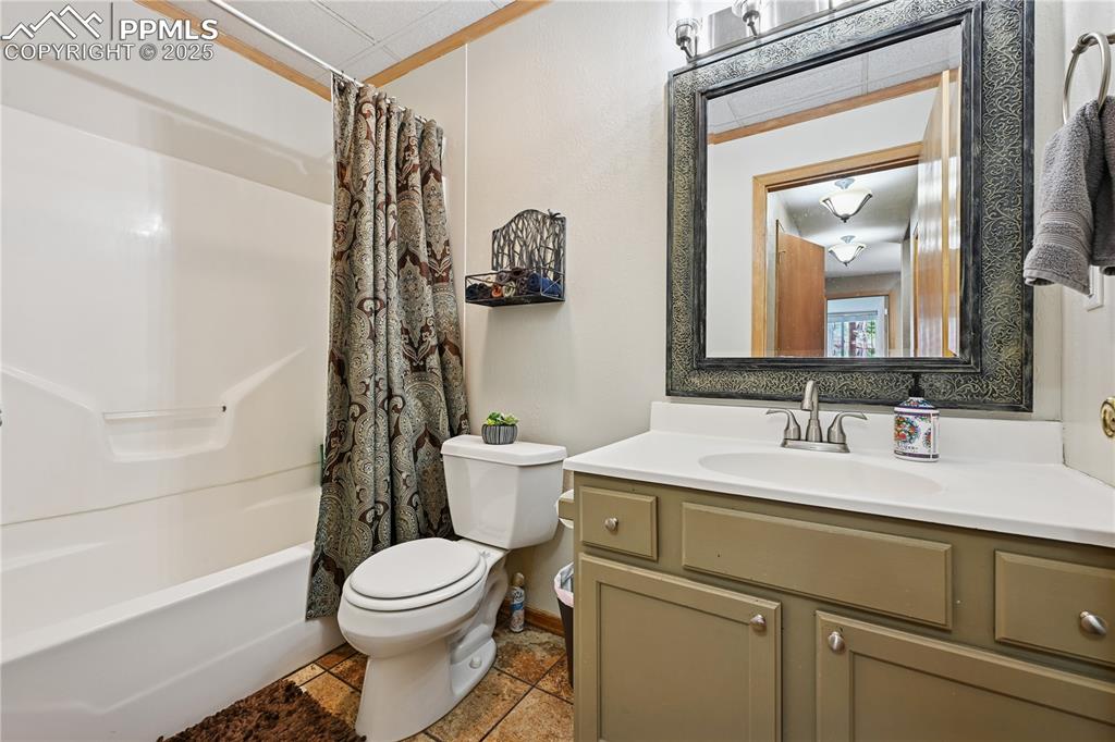 Image 18 of 34: Bathroom featuring shower / tub combo with curtain, vanity, and tile patter