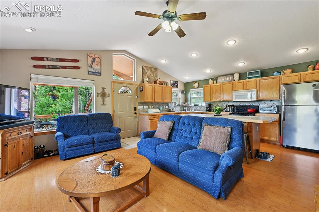 Image 24 of 34: Living room featuring lofted ceiling, light wood-style floors, a ceiling fa