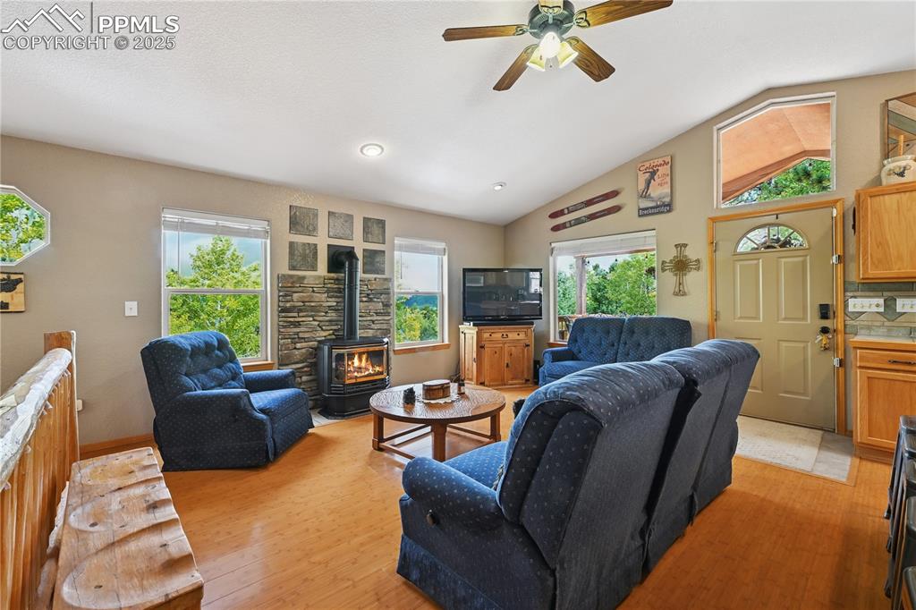 Image 25 of 34: Living area featuring a gas stove, lofted ceiling, light wood-style floorin