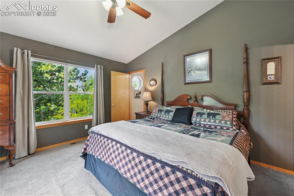 Image 31 of 34: Bedroom with vaulted ceiling, carpet floors, and ceiling fan