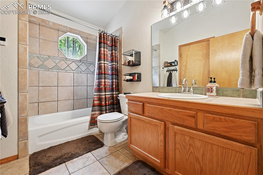 Image 34 of 34: Full bathroom featuring a textured wall, shower / bath combination with cur