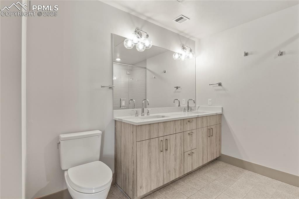 Image 9 of 22: Generously sized bathroom features a double vanity with quartz counters