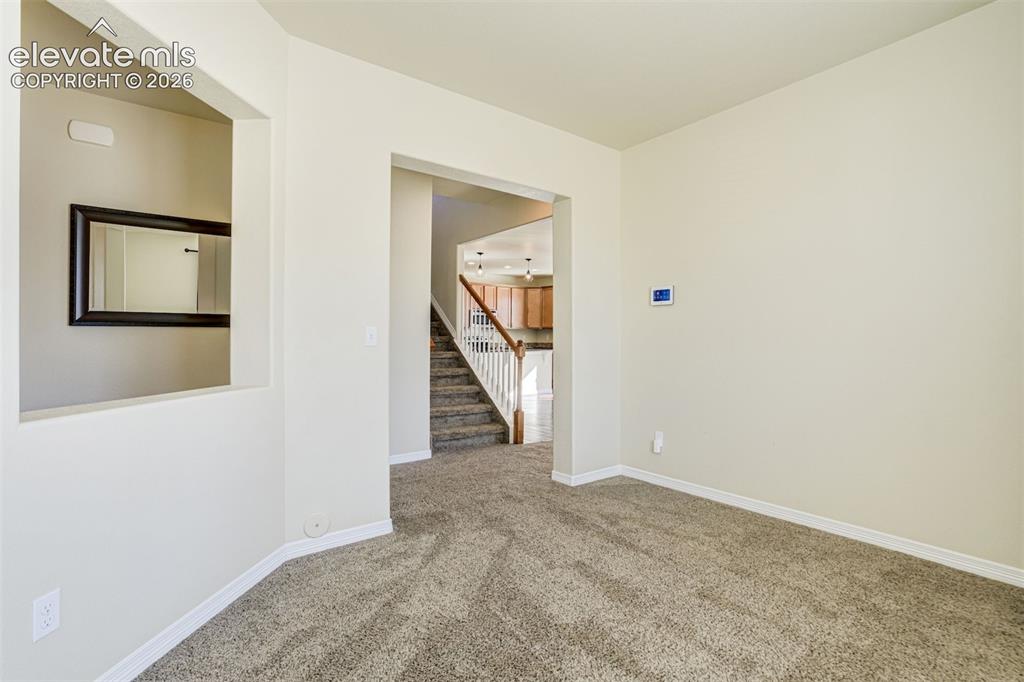 Image 10 of 49: Carpeted living space with neutral wall paint and a staircase with white ba