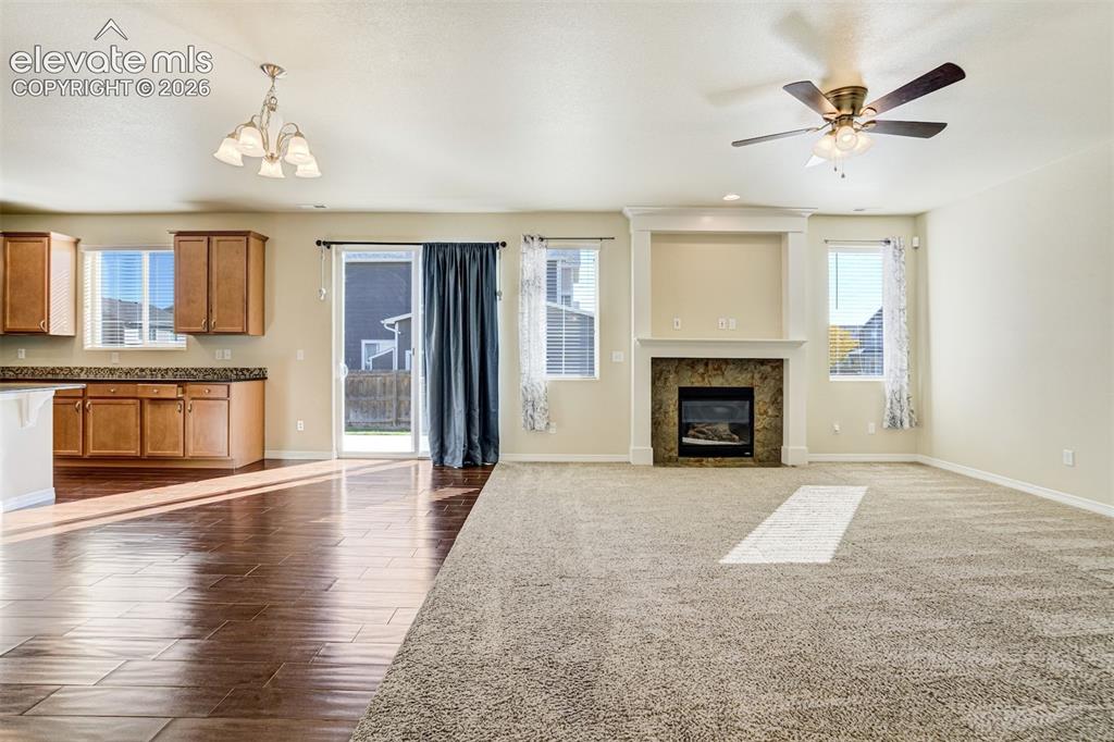 Image 12 of 49: Open-concept living area with a stone-surround fireplace, built-in media ni