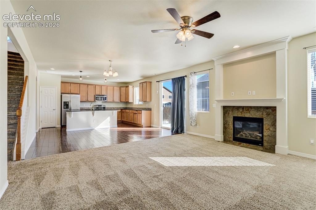 Image 13 of 49: Spacious living area with a built-in fireplace, ceiling fan, and sliding gl