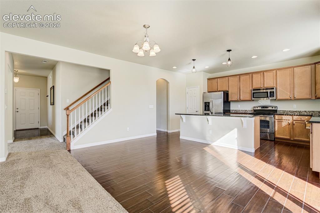 Image 14 of 49: Open-concept floor plan featuring wood-finish flooring, a kitchen island wi