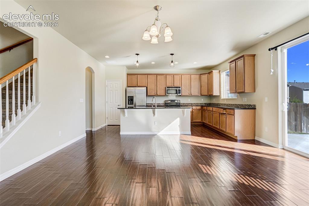 Image 15 of 49: Open concept living area featuring dark wood-finish flooring, a kitchen wit