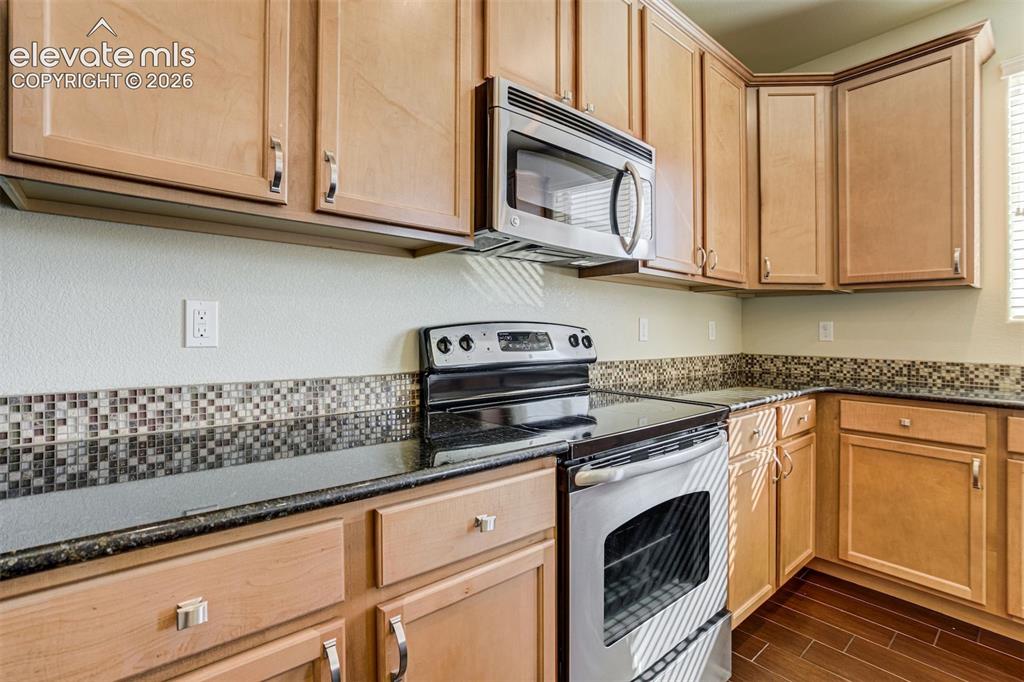 Image 18 of 49: Wood-finish cabinetry with silver-tone hardware, stainless steel microwave,