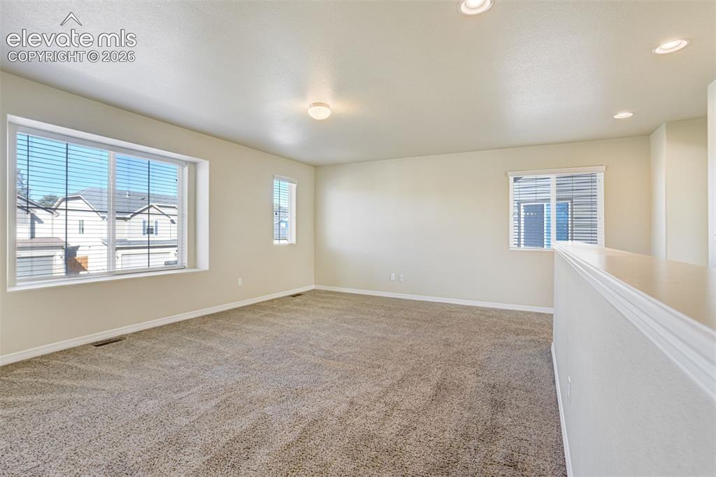 Image 23 of 49: Carpeted room with recessed lighting, a large picture window, and a seconda