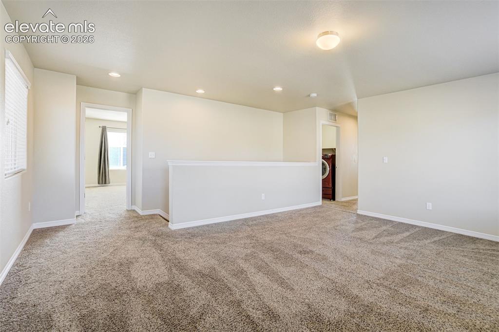 Image 24 of 49: Carpeted loft area with recessed lighting, a window with blinds, and a buil