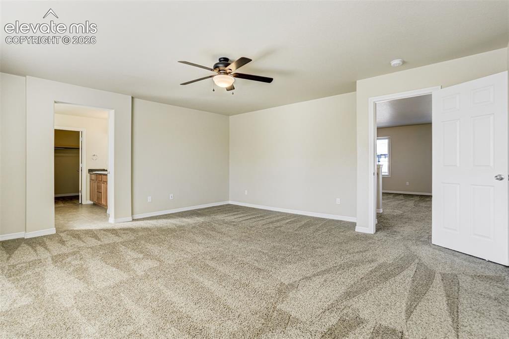 Image 27 of 49: Expansive room featuring neutral-toned walls, patterned carpeting, and a ce