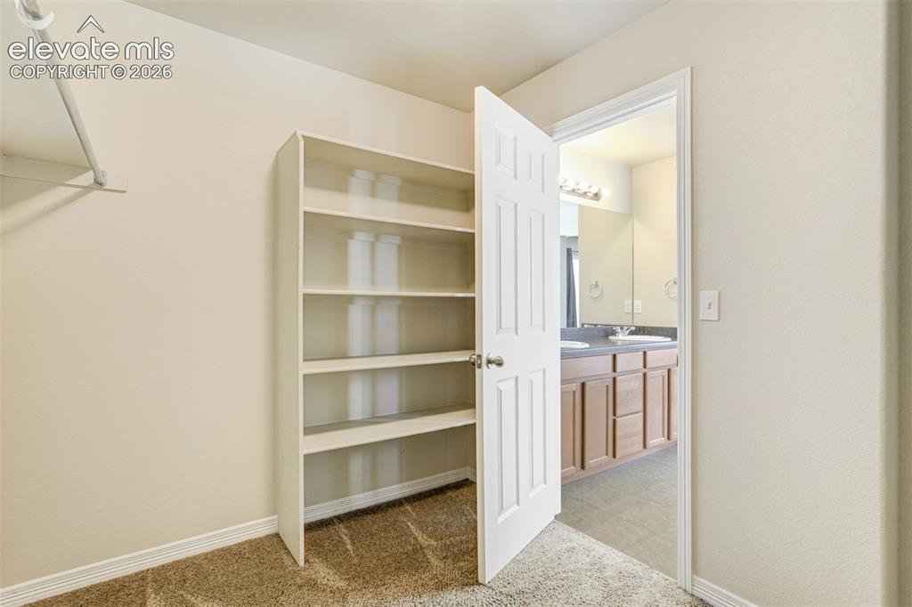 Image 32 of 49: Primary Closet with Built-in shelving unit, clothing rod, five-panel interi