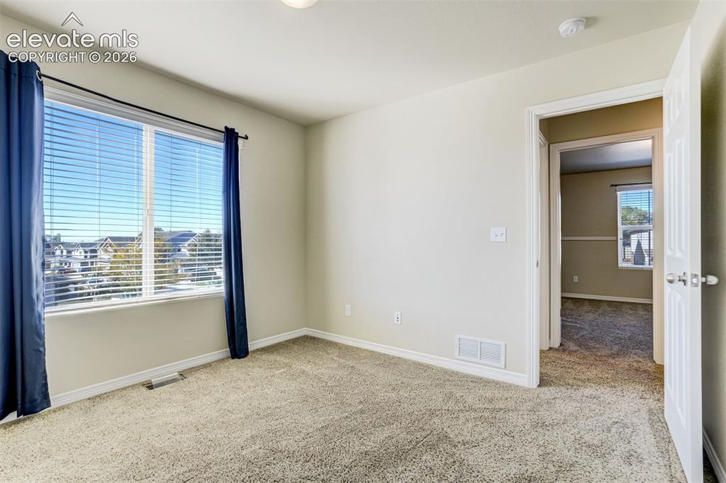 Image 33 of 49: Carpeted flooring, white walls, large window with blinds, white trim, and a