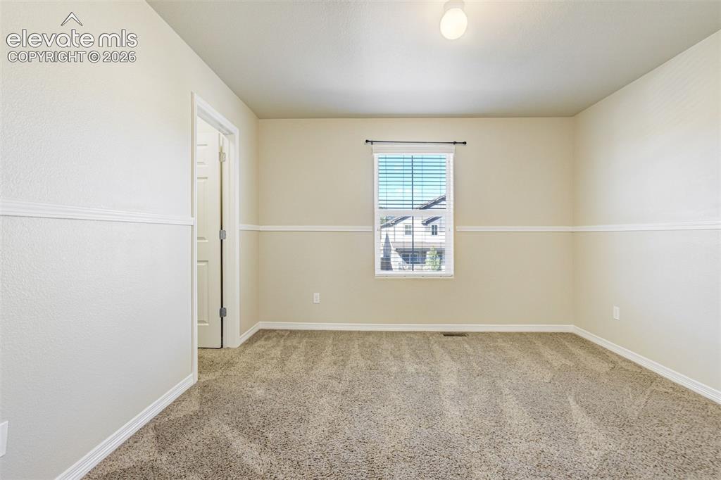 Image 35 of 49: Neutral-toned wall paint, textured carpeting, window with blinds, overhead 