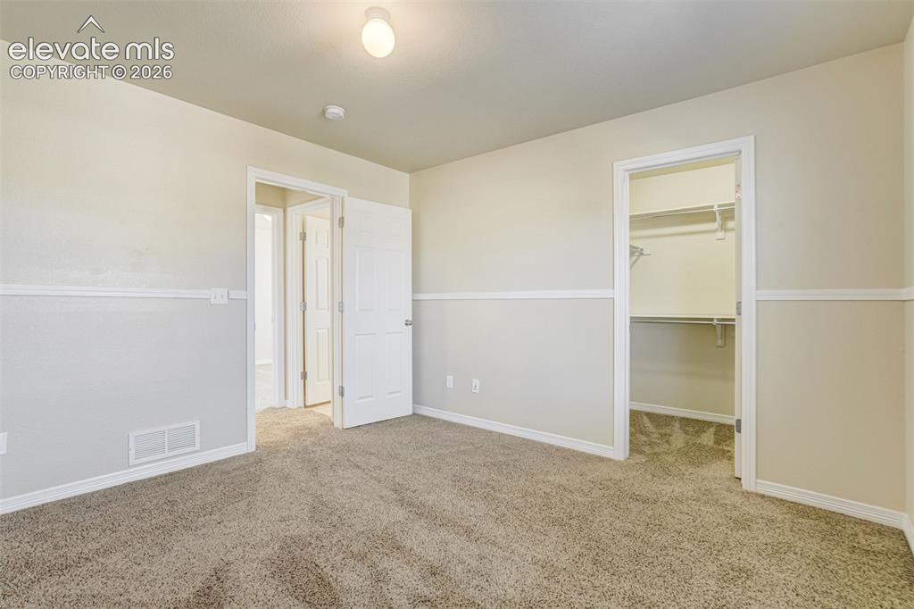 Image 36 of 49: Secondary Bedroom. Carpeted room with neutral wall tones and white trim and