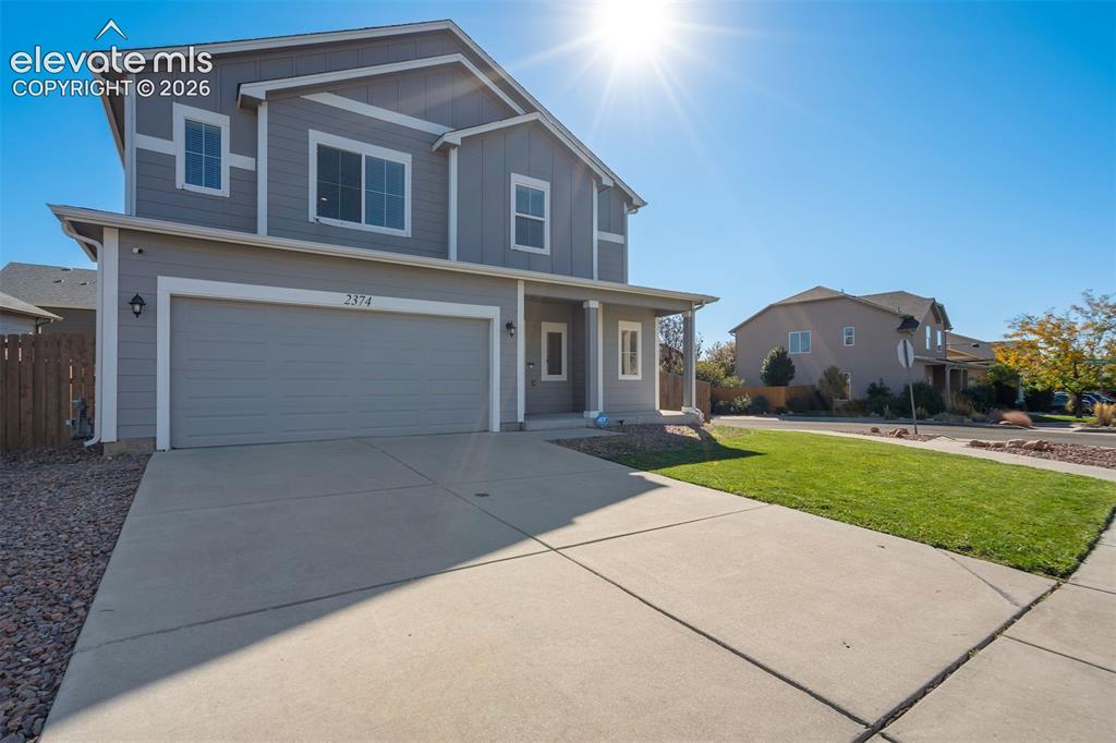 Image 4 of 49: Two-story residence with a two-car garage, concrete driveway, and a covered