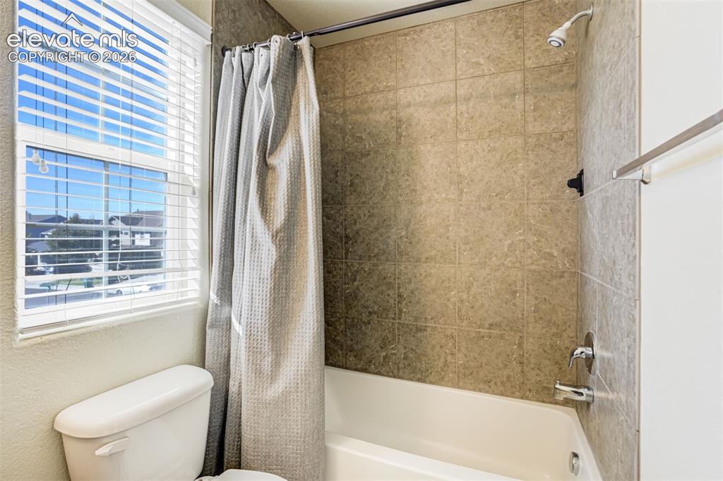 Image 40 of 49: Full Bath on Upper level.  Bathtub with a tiled surround, a white toilet, a