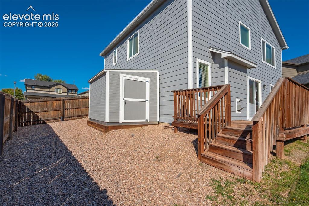 Image 43 of 49: Rear exterior featuring a wooden deck with stairs, sliding glass door, an e