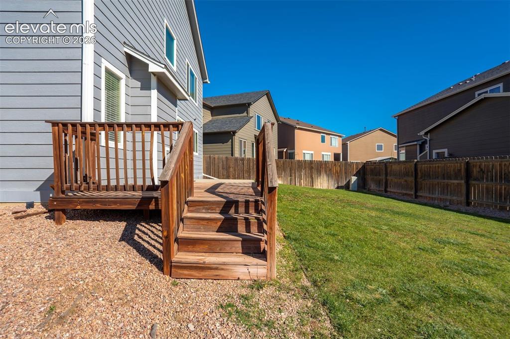 Image 44 of 49: Wooden deck with stairs, graveled area walk to shed