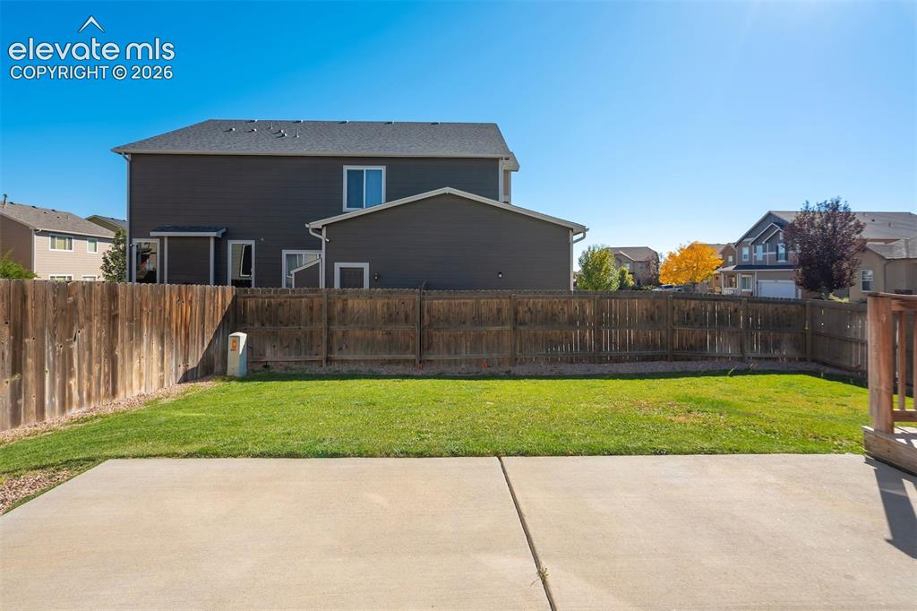 Image 45 of 49: Expansive backyard featuring a manicured lawn, concrete patio, and full per