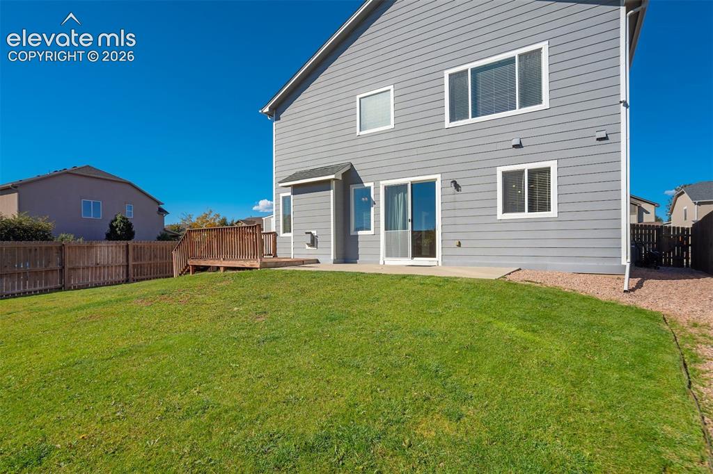 Image 47 of 49: Expansive green lawn with a wood privacy fence, concrete patio, and a wood