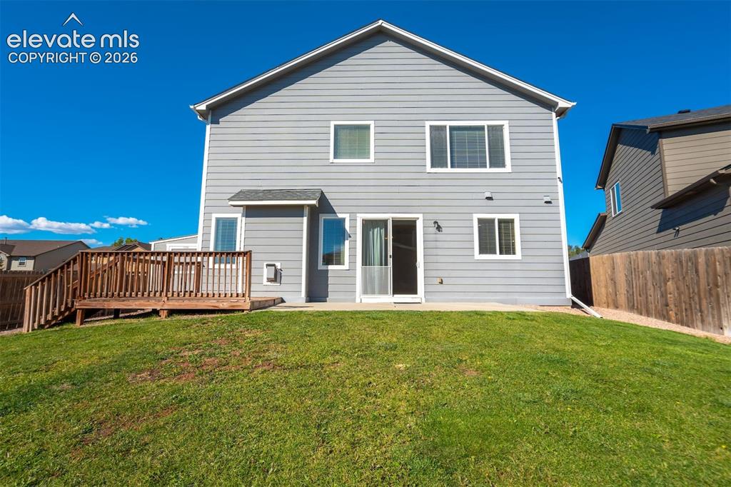 Image 48 of 49: Rear exterior with light gray siding, multiple windows, a ground-level pati