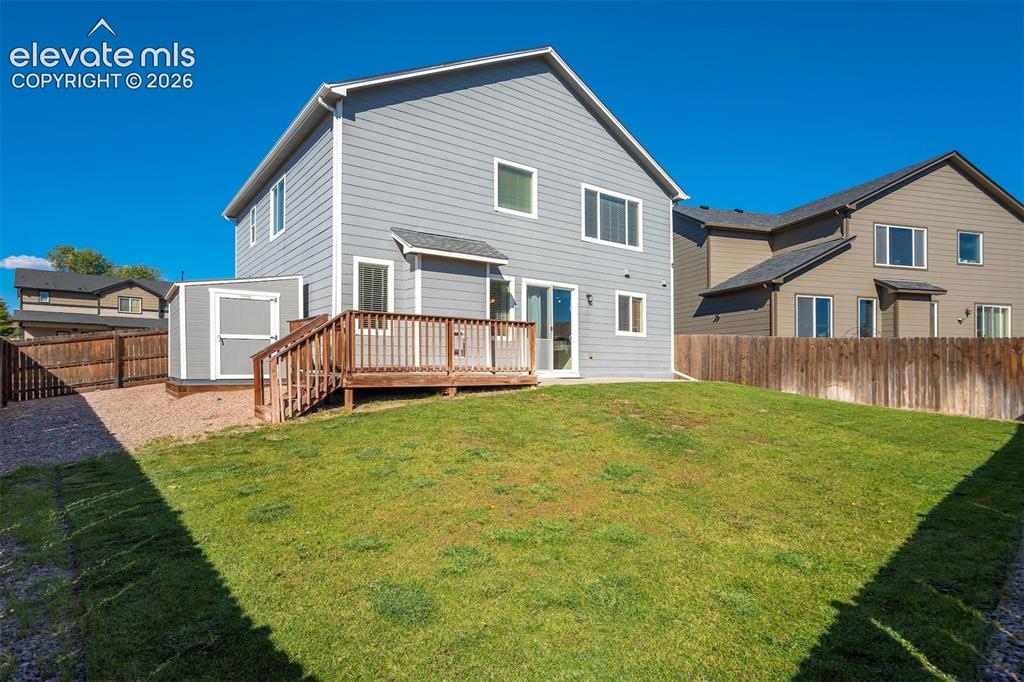 Image 49 of 49: Expansive backyard with a manicured lawn, a wooden deck with railing, and a