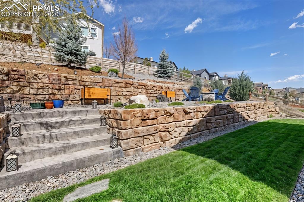 Image 45 of 50: The beautifully terraced, fully landscaped yard is framed by elegant stone 