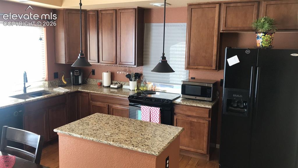 Image 4 of 10: Kitchen featuring wood-finish cabinetry, granite countertops, a center isla