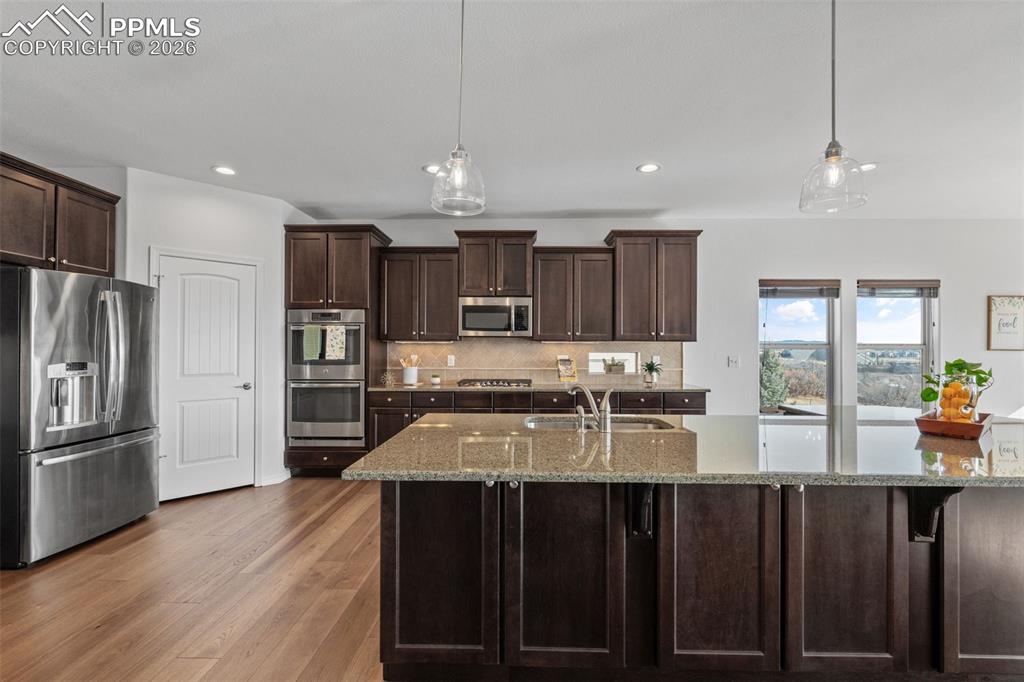 Image 12 of 48: Kitchen with dark wood finish cabinetry, stainless steel appliances, light